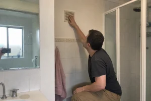 Person kontrollerar ventilationsgaller i badrum inför att flytta tvättmaskin badrum