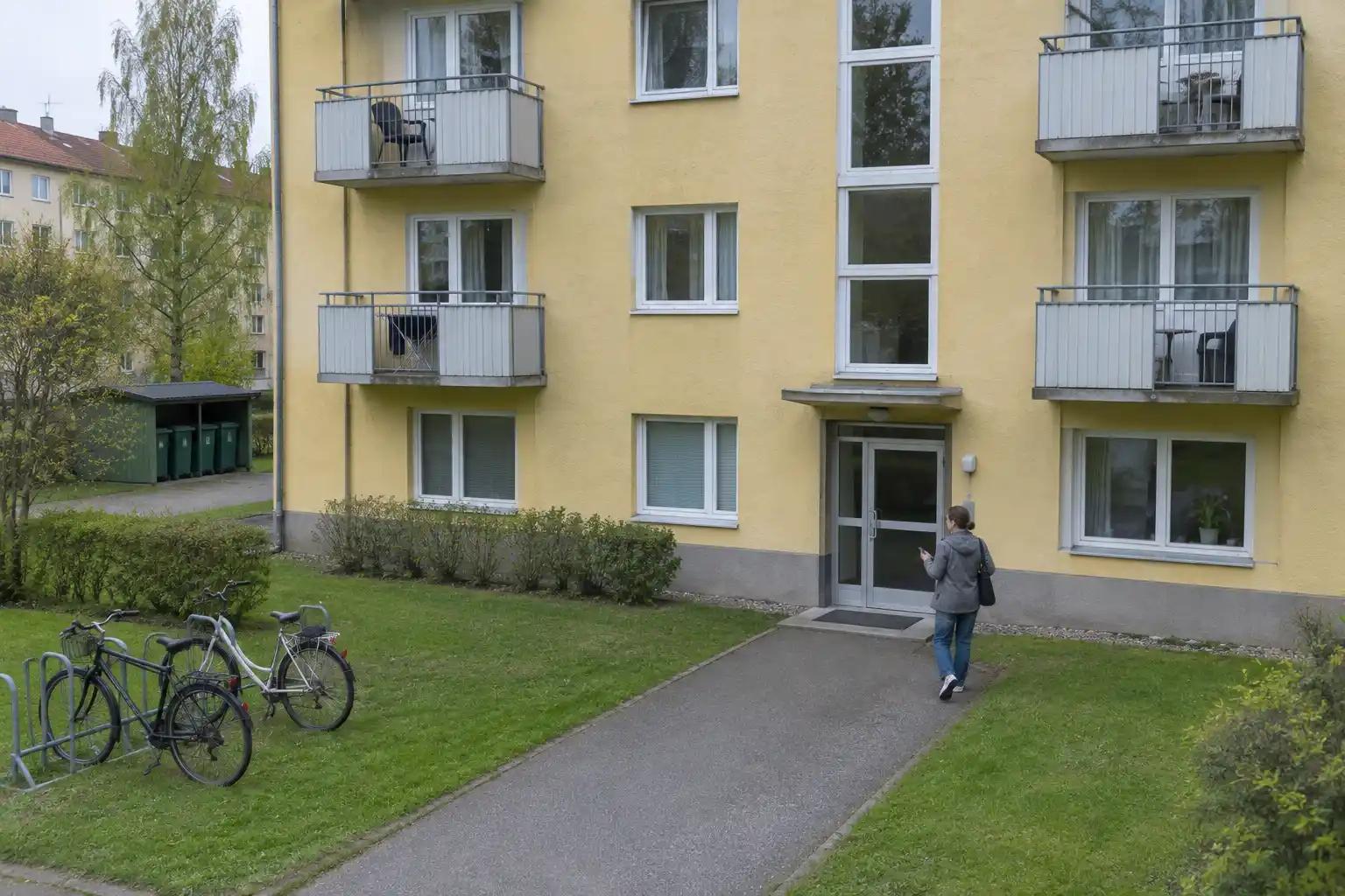 Person med nyckel i handen på väg mot porten till ett hyreshus där man kan hyra andrahand
